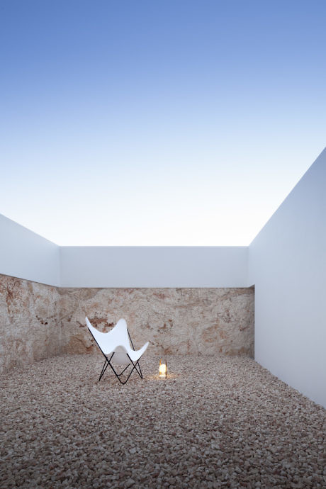 Minimalist courtyard with a single chair and pebble flooring