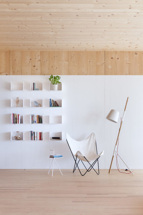 Minimalistic interior with wooden floors, white walls, a butterfly chair, floor lamp