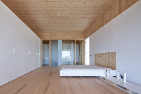Minimalist bedroom with light wood panels and a low platform bed.