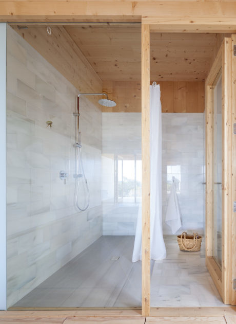 Minimalist wooden bathroom with glass shower enclosure.