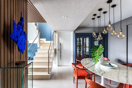 Modern home interior with stairs, dining area, and hanging lights.