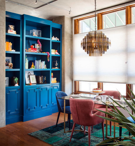 Modern dining room with blue built-in shelves, a wooden table, velvet chairs,