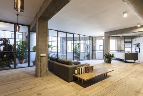 Modern interior with wooden floors, sectional sofa, and large windows.