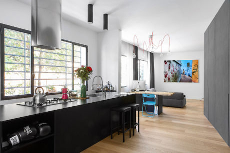 Sleek kitchen with black countertops and wooden floors.