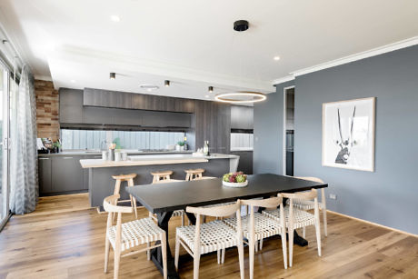 Modern kitchen with wood floors, gray cabinetry, dining table, and pendant lighting