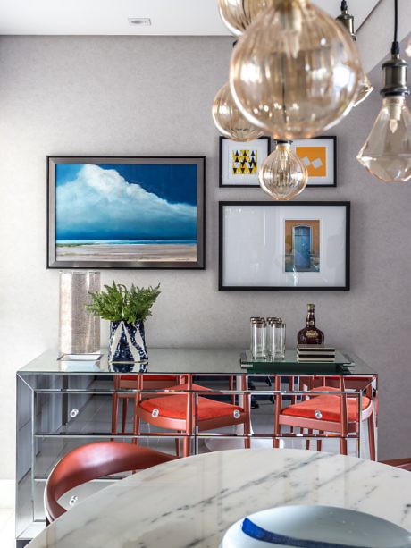 Contemporary dining space with chrome table, red chairs, and decorative pendant lights.