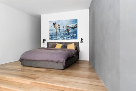 Minimalist bedroom with a large bed and a framed picture above it.