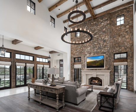 Spacious living room with stone fireplace and large circular chandeliers.