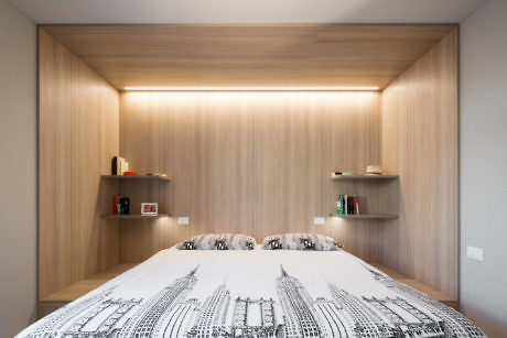 Minimalist bedroom with wood panel walls and hidden lighting.