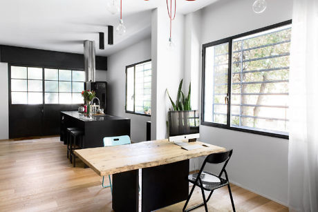 Sleek kitchen with contrasting black cabinets, wood floors, and pops of red