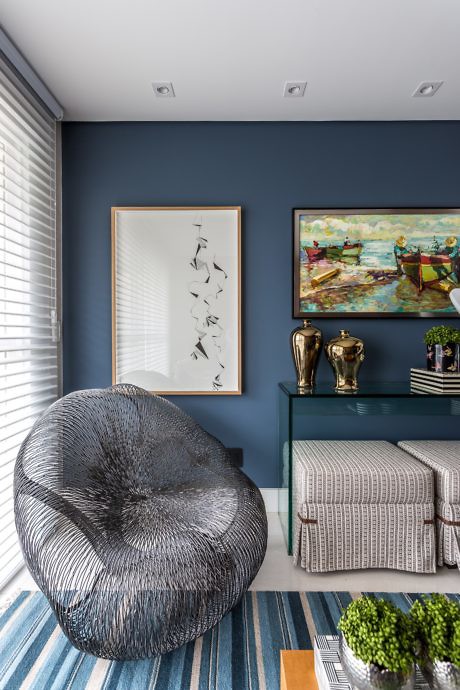 Modern room with blue walls, artwork, a textured chair, and decorative shelving
