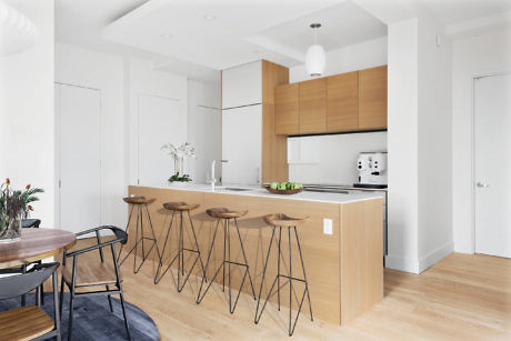 Modern kitchen with island and bar stools, adjacent dining area.