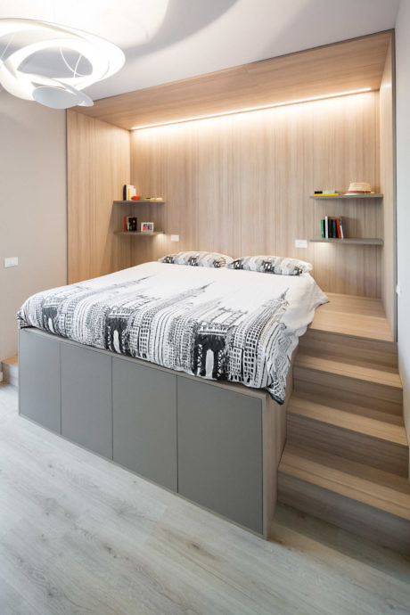 Modern bedroom with built-in shelving, LED lighting, and a raised bed platform