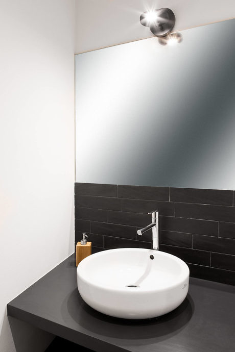 Modern bathroom with round vessel sink, wall faucet, and mirror.
