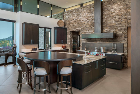 Contemporary kitchen with stone walls and oval island.