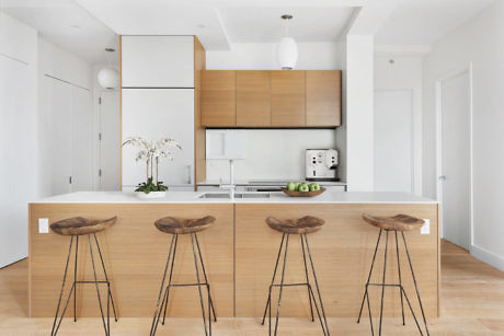 Minimalist kitchen with wooden cabinets and bar stools.
