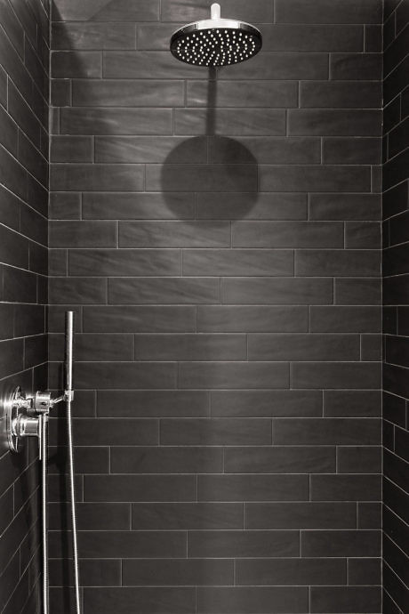 Modern shower with dark tiles and a large showerhead.
