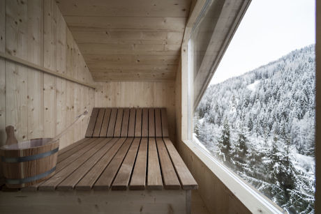 Wooden sauna interior with a forest view through the window.