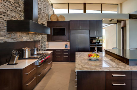 Modern kitchen interior with dark cabinets and stone wall.