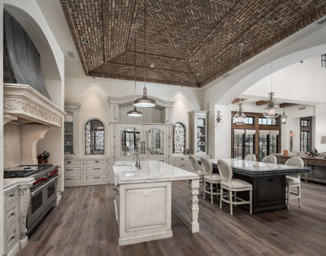 Elegant kitchen with island, marble countertops, and herringbone ceiling.