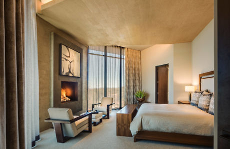 Contemporary bedroom with fireplace, large window, and neutral tones.