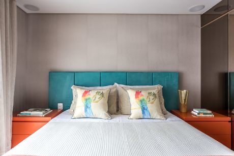 Contemporary bedroom with teal headboard and orange nightstands.
