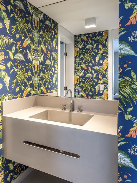 Bathroom with tropical wallpaper and a sleek white vanity.