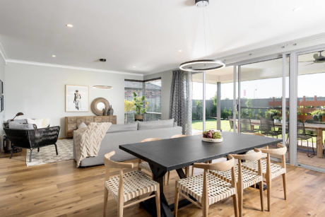 Modern living room with dining area, sofa, and sliding doors to garden.