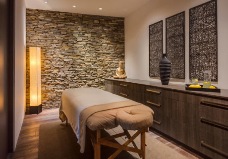 A serene spa room with a massage table, stone wall decor, and warm ambient