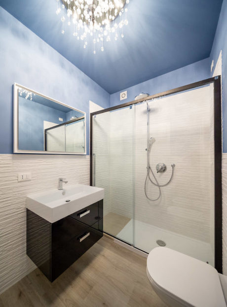 Contemporary bathroom with blue walls and chic chandelier.