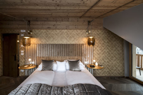 Contemporary wooden bedroom with patterned headboard and pendant lights.