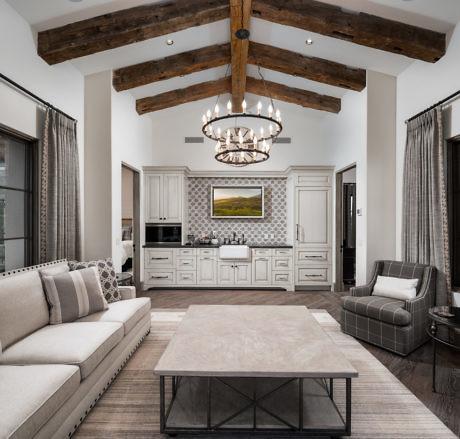 Elegant living room with wooden beams, chandelier, and neutral tones.