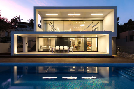 Modern house with large windows and pool at dusk.