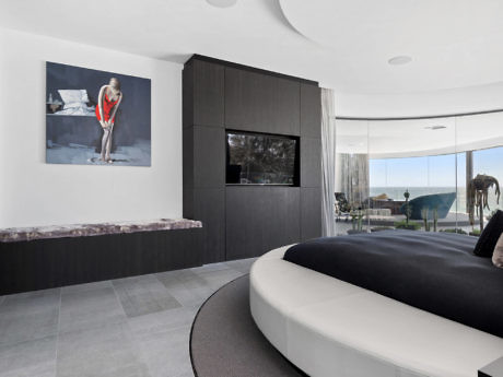 Sleek interior with curved bed, artwork, and panoramic view.
