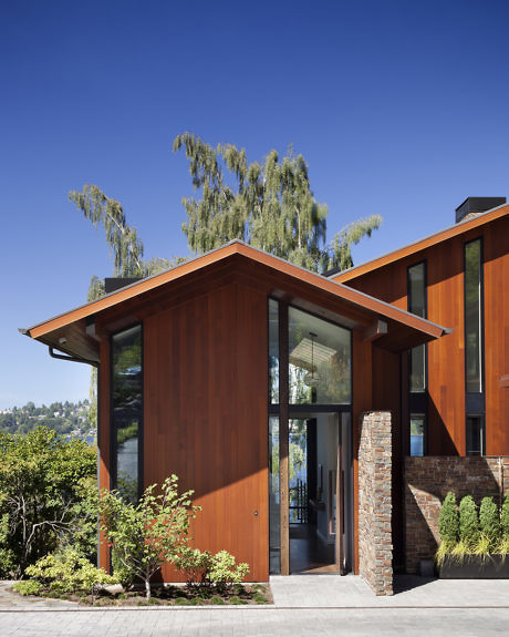 Modern house with large windows and wooden exterior against a blue sky.