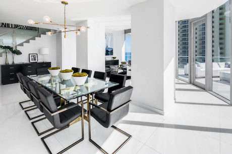 Modern dining room with black chairs, glass table, and white interior.