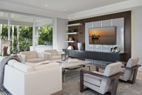 Modern living room with sofa, chairs, and large wall-mounted TV.