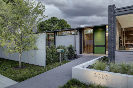 Modern house facade with green door and concrete pathway