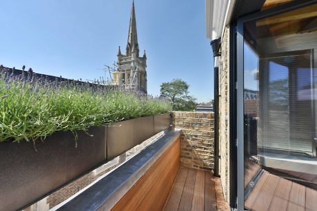 Urban balcony garden with a view of a church spire.