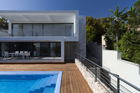 Modern house with large windows overlooking a pool and deck.
