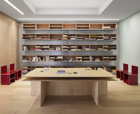Sleek office with large wooden bookshelf and minimalist desk flanked by red