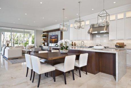 Modern kitchen with white cabinets and island connected to a dining area with a wooden table