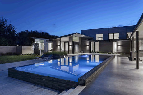 Contemporary house with illuminated pool at dusk.