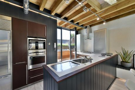 Contemporary kitchen with wooden beams, sleek cabinets, and curved island.