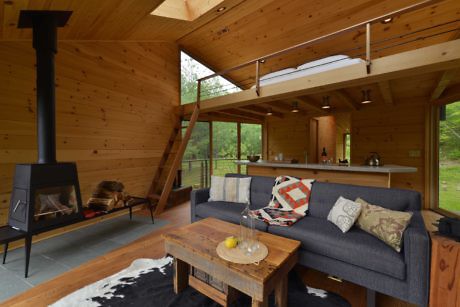 Modern wooden cabin interior with fireplace and cozy furnishings.