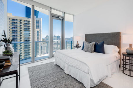 Modern bedroom with large window overlooking cityscape.