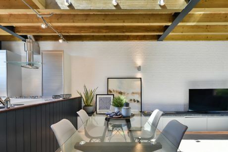Modern kitchen and dining area with wooden ceiling and white walls.