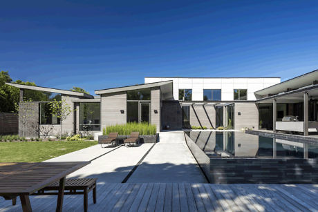 Contemporary home with pool and wooden deck under a clear sky.