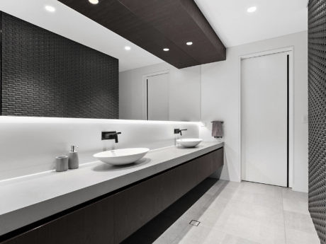 Modern bathroom interior with dual sinks and black tile wall.