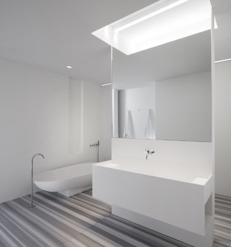 Modern minimalist bathroom with backlit mirror and white fixtures.